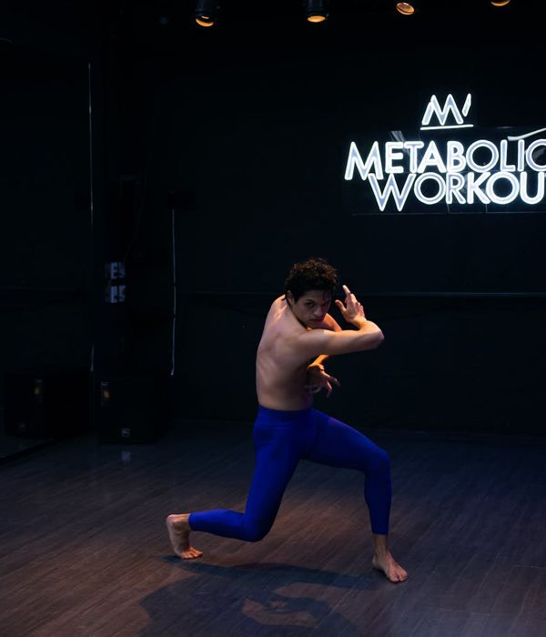 Young woman performing stretching exercises in a bright modern studio with neon lighting elements.